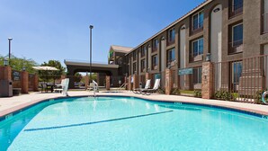 Una piscina con lettini e un edificio con numerose finestre e balconi.