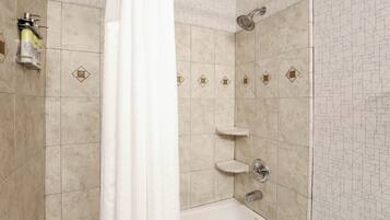 Un baño con bañera, ducha e inodoro. Hay azulejos decorativos en las paredes y una toalla colgada.