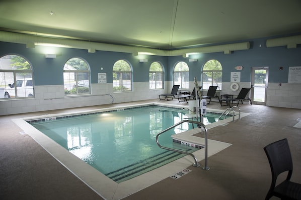 An indoor swimming pool with clear water, multiple lanes, and safety railings.