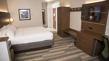 A hotel room with a bed, a desk, a TV, and a wardrobe.