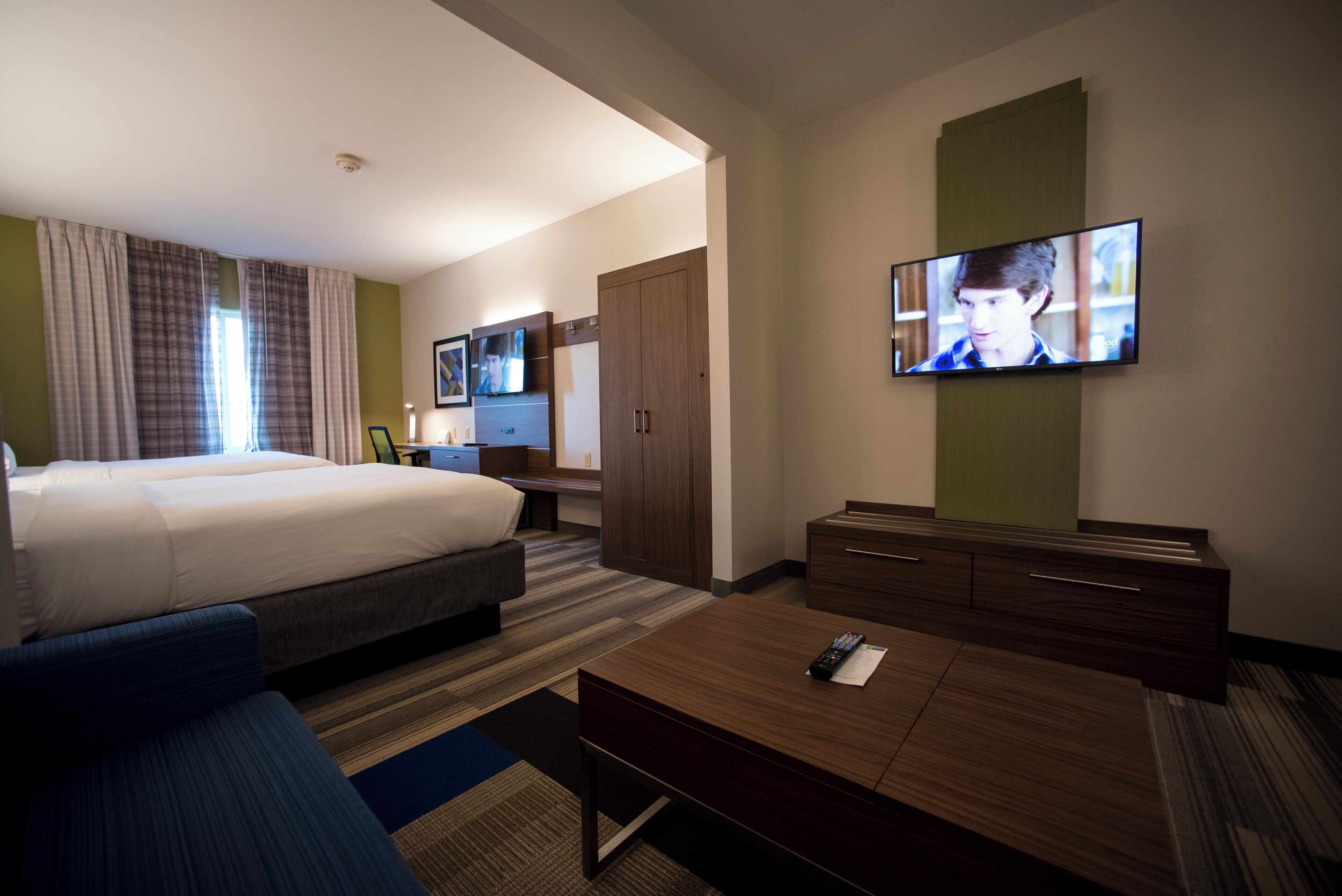 Een hotelkamer met een bed, bureau, televisie en kledingkast.