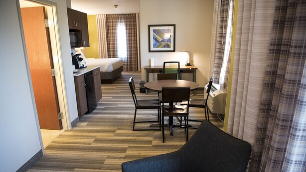 Una habitación de hotel con cama, escritorio y silla, mesa de comedor con sillas y sofá.