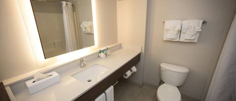 Un baño moderno con un espejo grande, un lavamanos, un inodoro y un perchero para toallas.