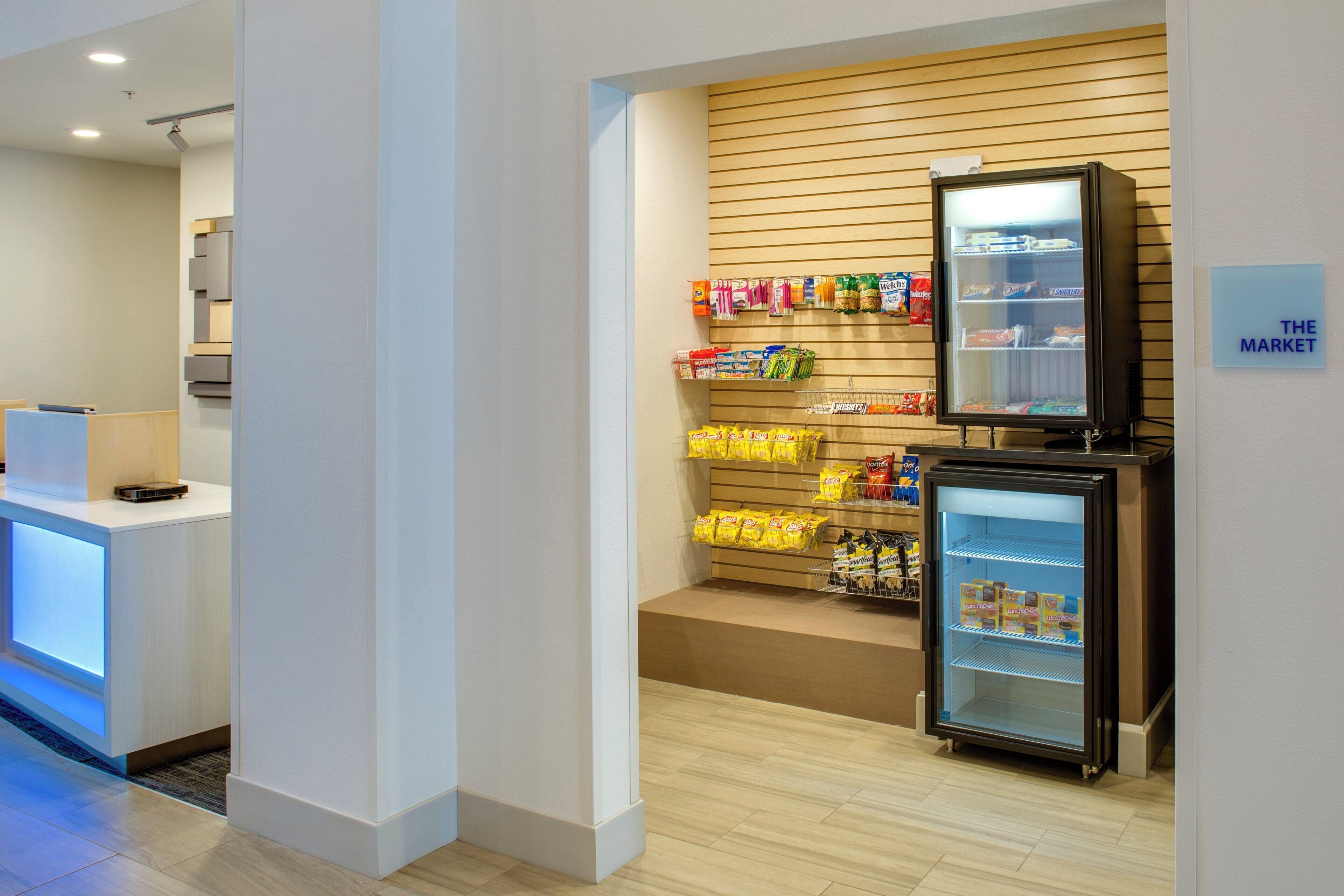 Un'hall dell'hotel con una reception, un bar per spuntini e un frigorifero fornito di snack.