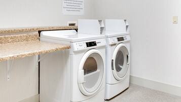 A guest laundry area with two front-loading washing machines and a countertop.
