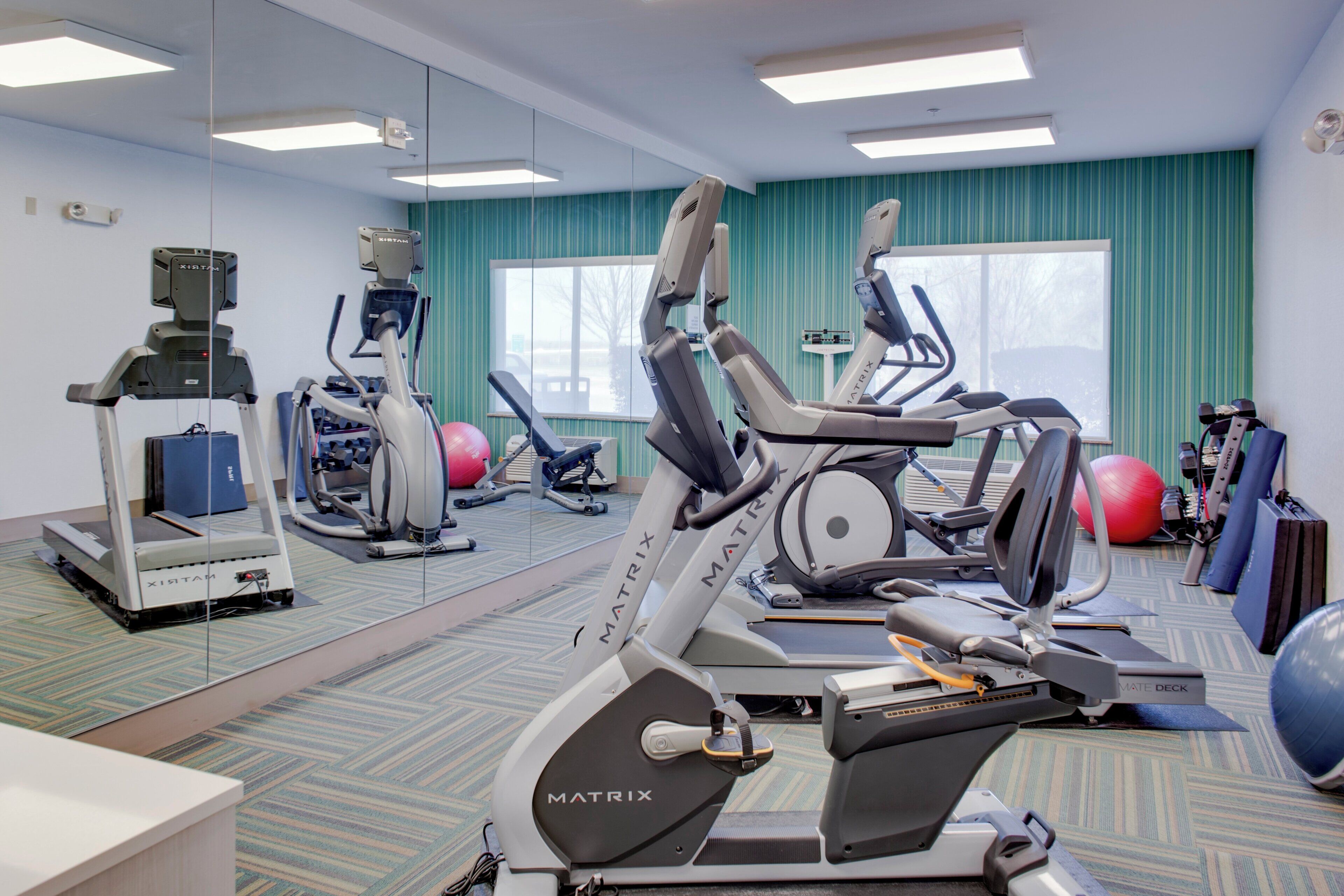 Un gimnasio con bicicletas estáticas, cintas de correr y pelotas de ejercicio.