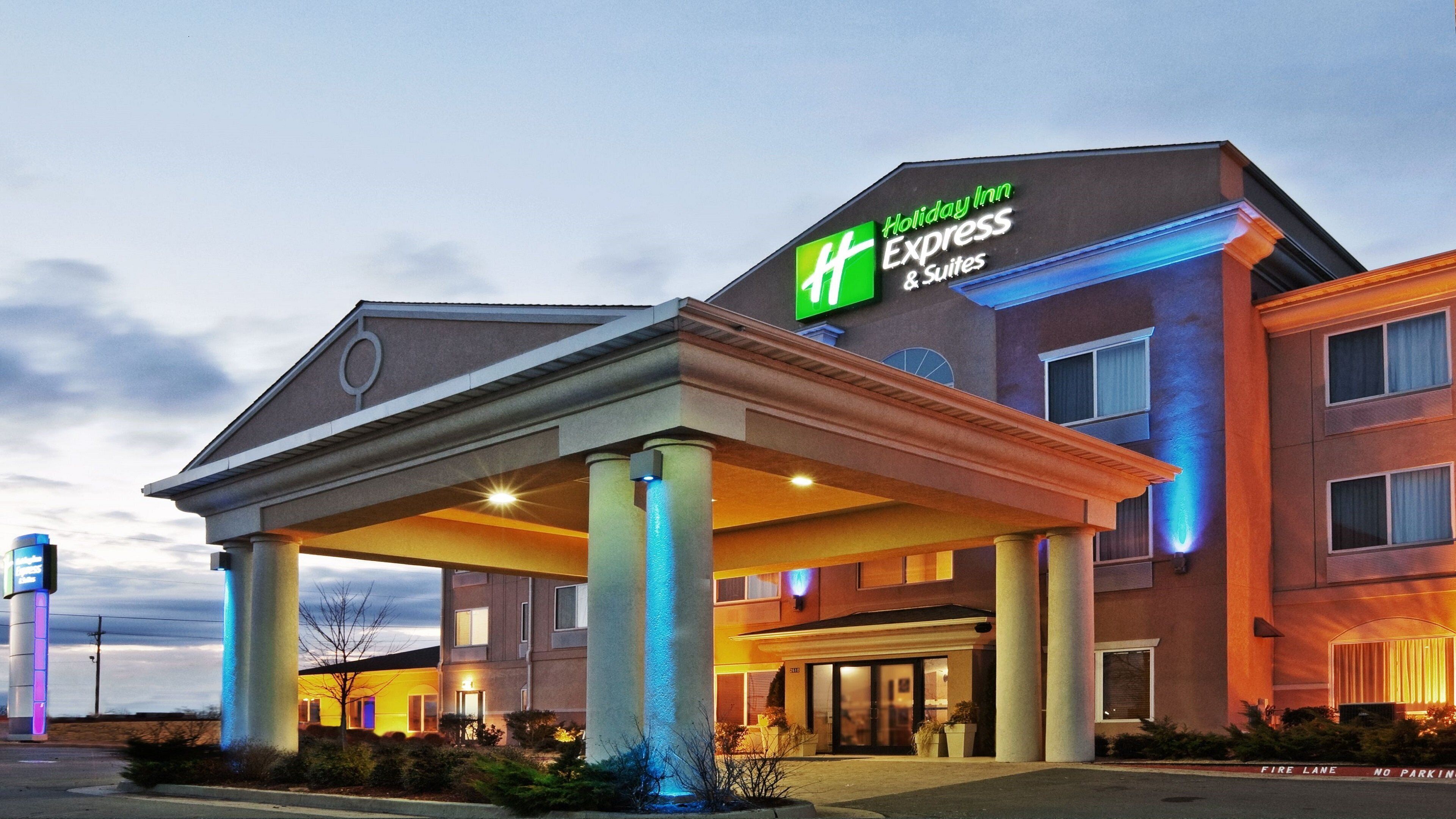 A Holiday Inn Express & Suites building with a covered entrance and a sign indicating it's a Holiday Inn Express & Suites.