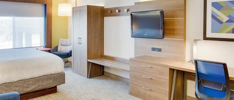 A hotel room with a bed, a desk, a chair, a television, and a window.