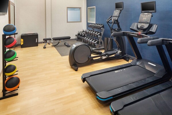 A gym with treadmills, dumbbells, and exercise balls.