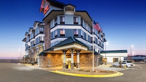 A multi-story hotel with a prominent American flag, a covered entrance, and a parking area. - Hampton Inn & Suites Parker (Parker)