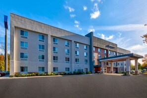 A multi-story hotel with a modern design, featuring a covered entrance and a parking area. - Hampton Inn Waterbury (Waterbury)