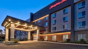 A Hampton Inn hotel with a modern design, featuring a well-lit entrance and multiple floors.