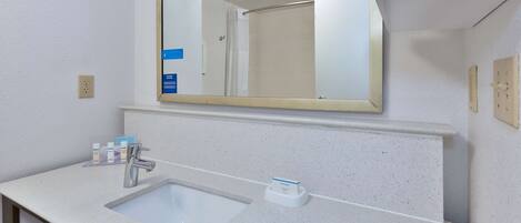 A bathroom with a white sink, a mirror, and a shower.