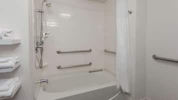 A modern bathroom with a bathtub, grab bars, and a shower.