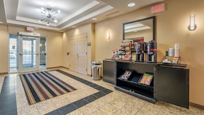 Um hall de hotel com balcão de recepção, espaço para café, lixeira e placa de saída.