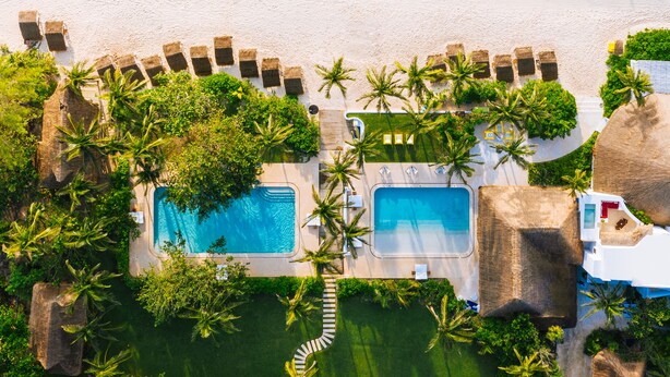 Oversigtsbillede af et resort med to swimmingpools, en strand og frodig vegetation.