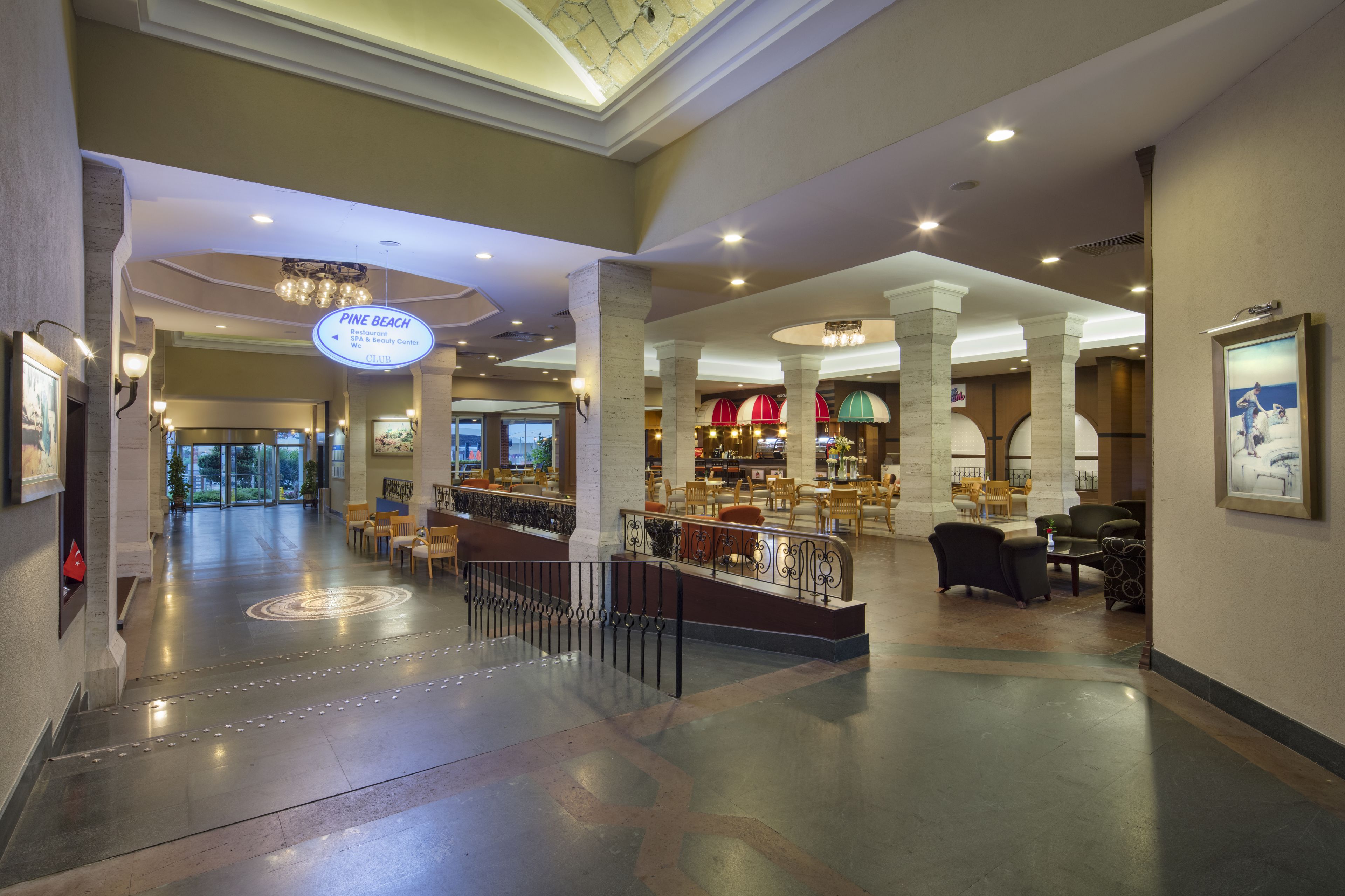 A spacious lobby with a central seating area, a reception desk, and a sign indicating the Pine Beach Club.