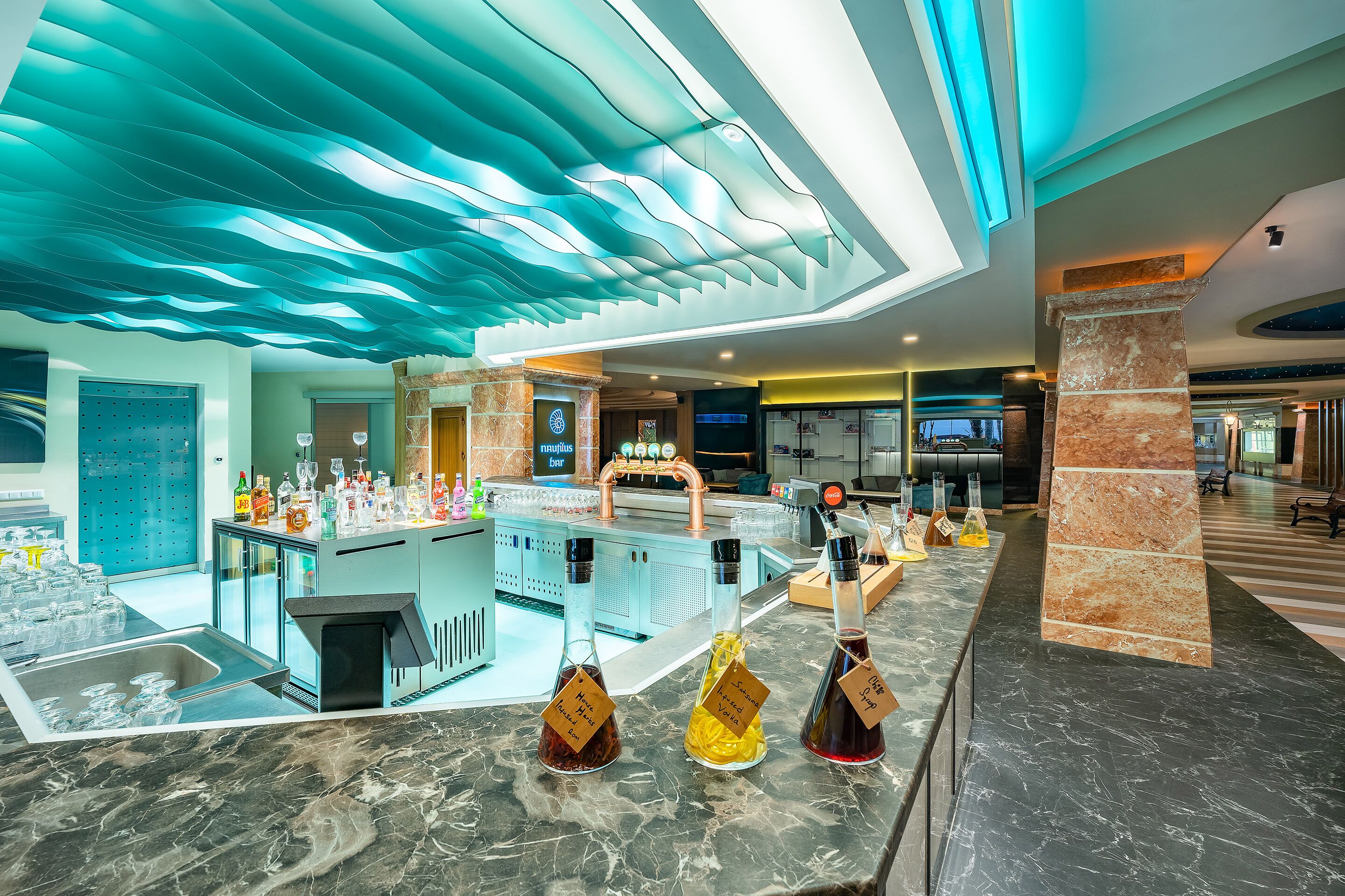 Een moderne bar met een marmeren aanrechtblad, een opvallend plafondontwerp en een ruimtelijke indeling.