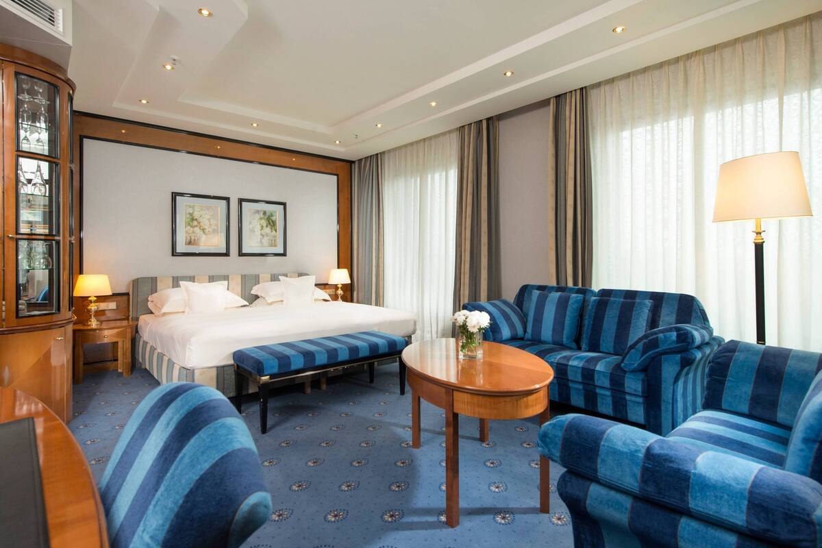 Ein Hotelzimmer mit Bett, einer Couch, einem kleinen Tisch und einer Lampe.