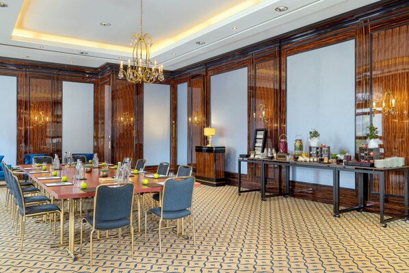 Un salón de conferencias con una larga mesa, sillas y una zona de buffet.