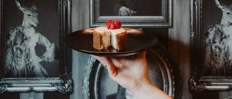 Una mano sosteniendo un pastel con una porción cortada, sobre un plato negro.