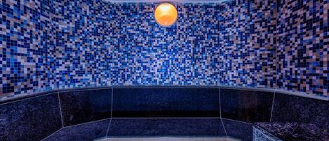 Un baño con paredes de mosaico y una lámpara central.
