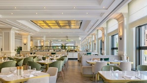 A spacious hotel dining area with multiple seating arrangements, a central bar, and large windows providing natural light. - JW Marriott Hotel Berlin (Berlin)