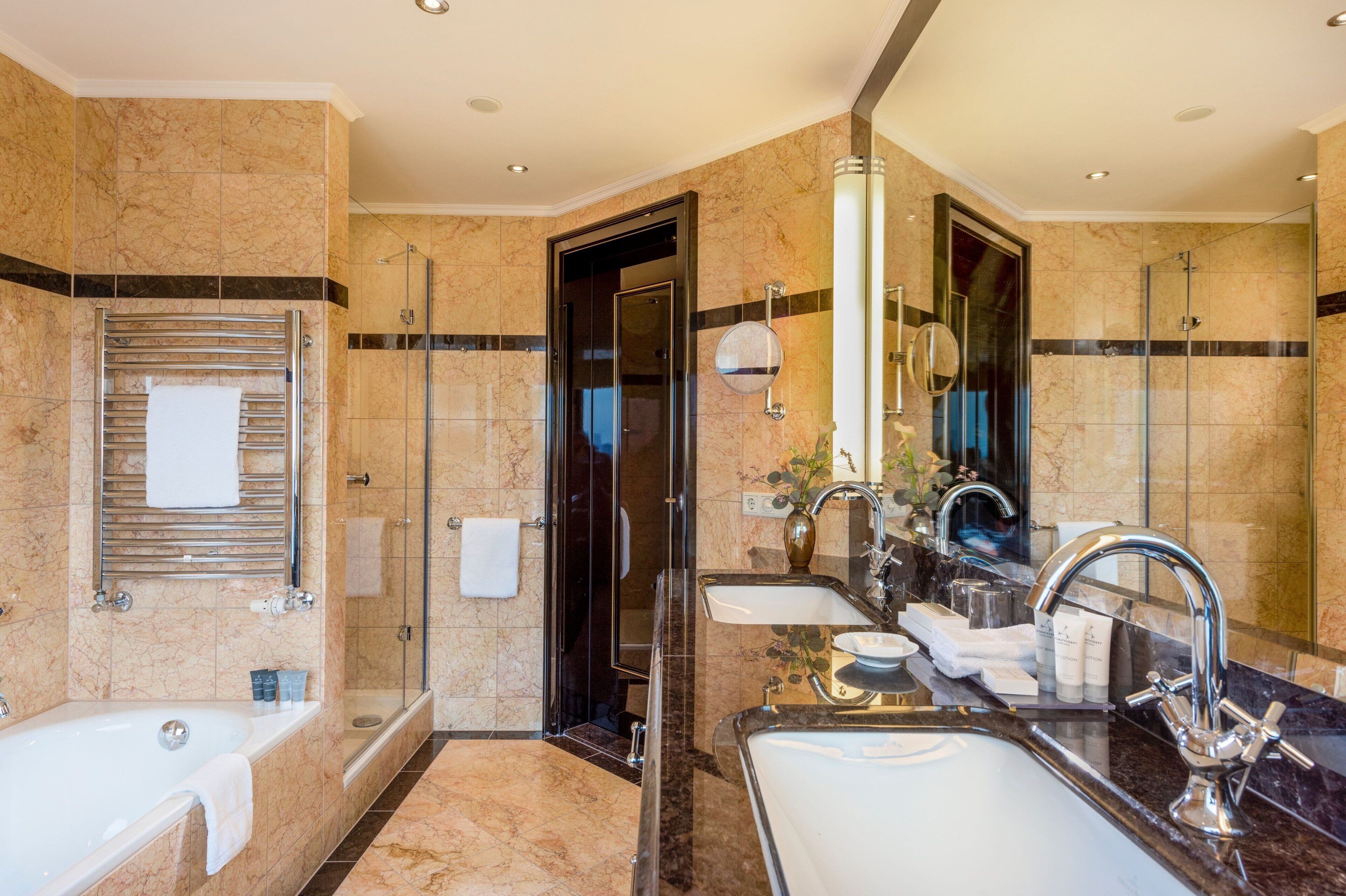 A luxurious bathroom with a large bathtub, a separate shower area, and a vanity with a sink and mirror.