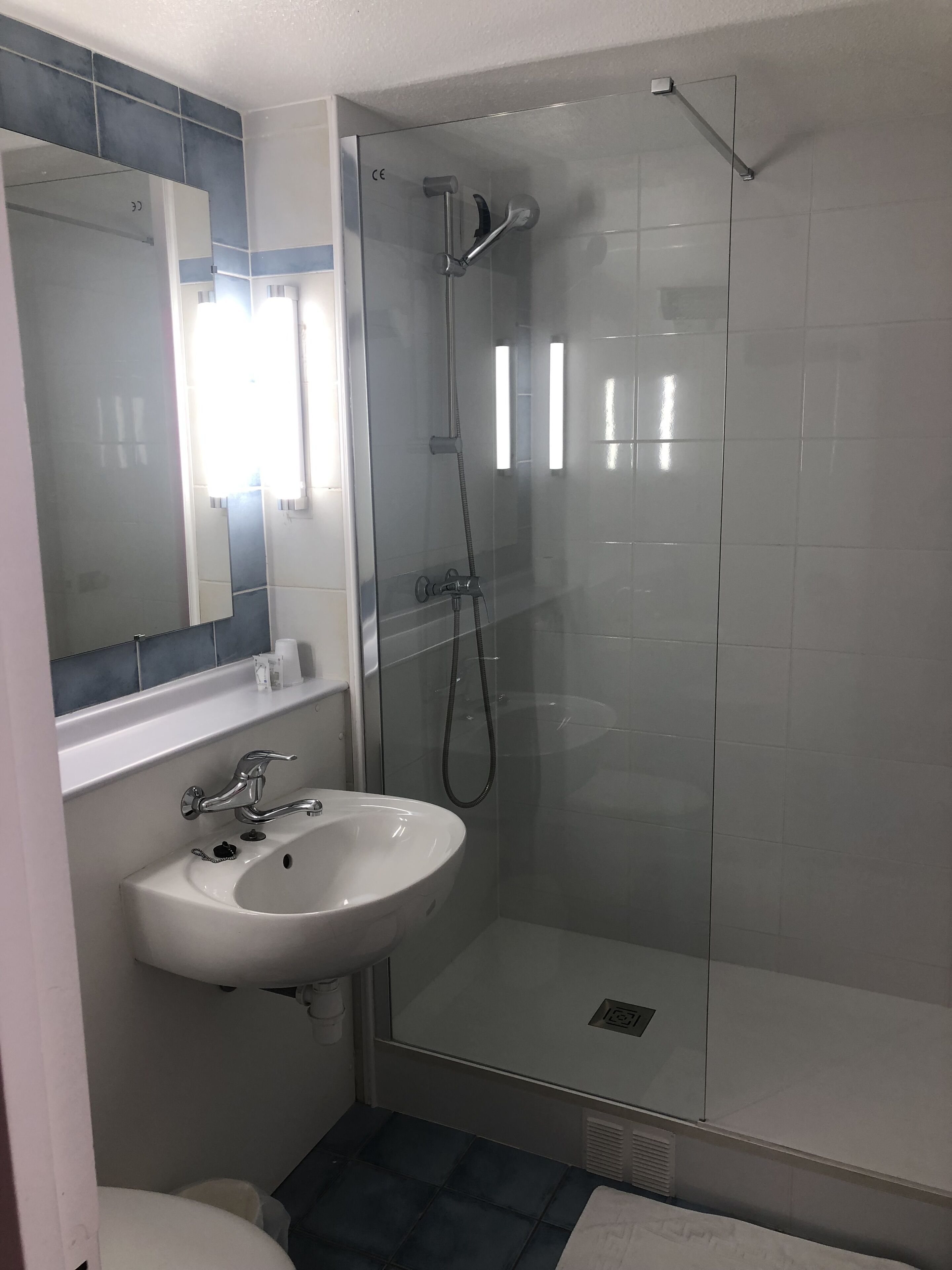 A bathroom with a glass-enclosed shower, a white sink, and a mirror.