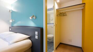 A hotel room with a bed, a bathroom with a toilet, and a shower area.