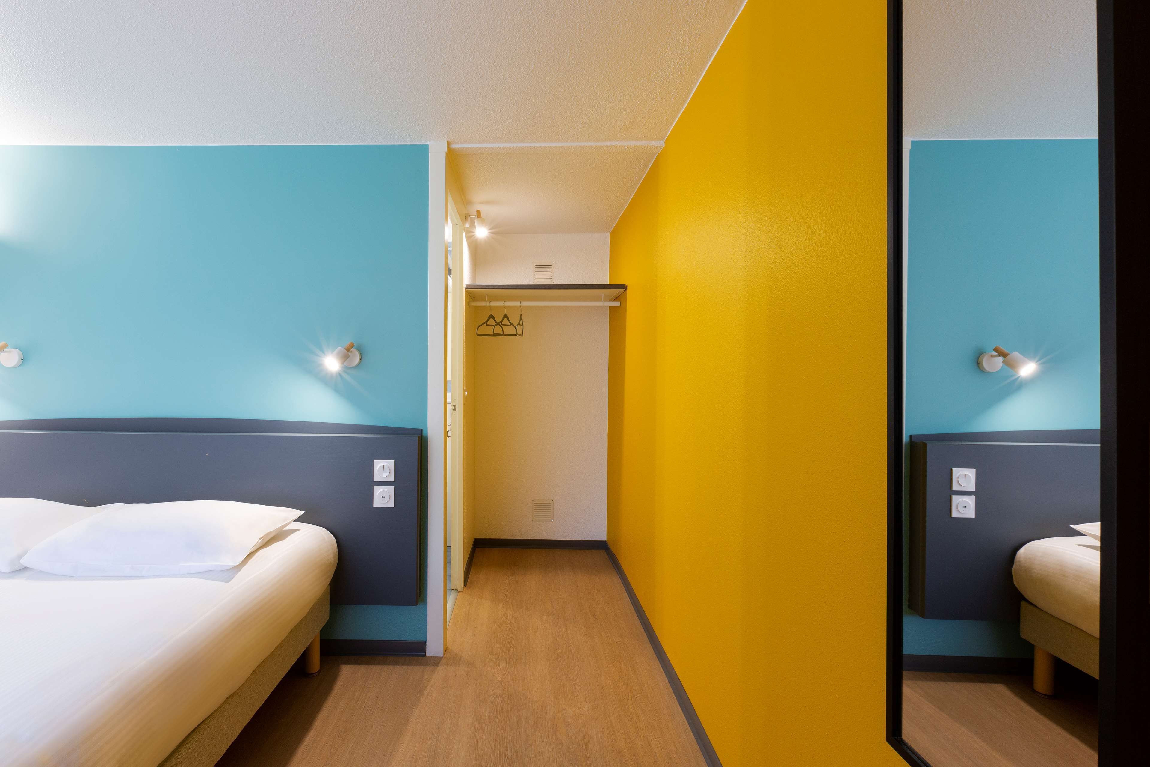 Une chambre d’hôtel avec un lit, une armoire et un miroir.
