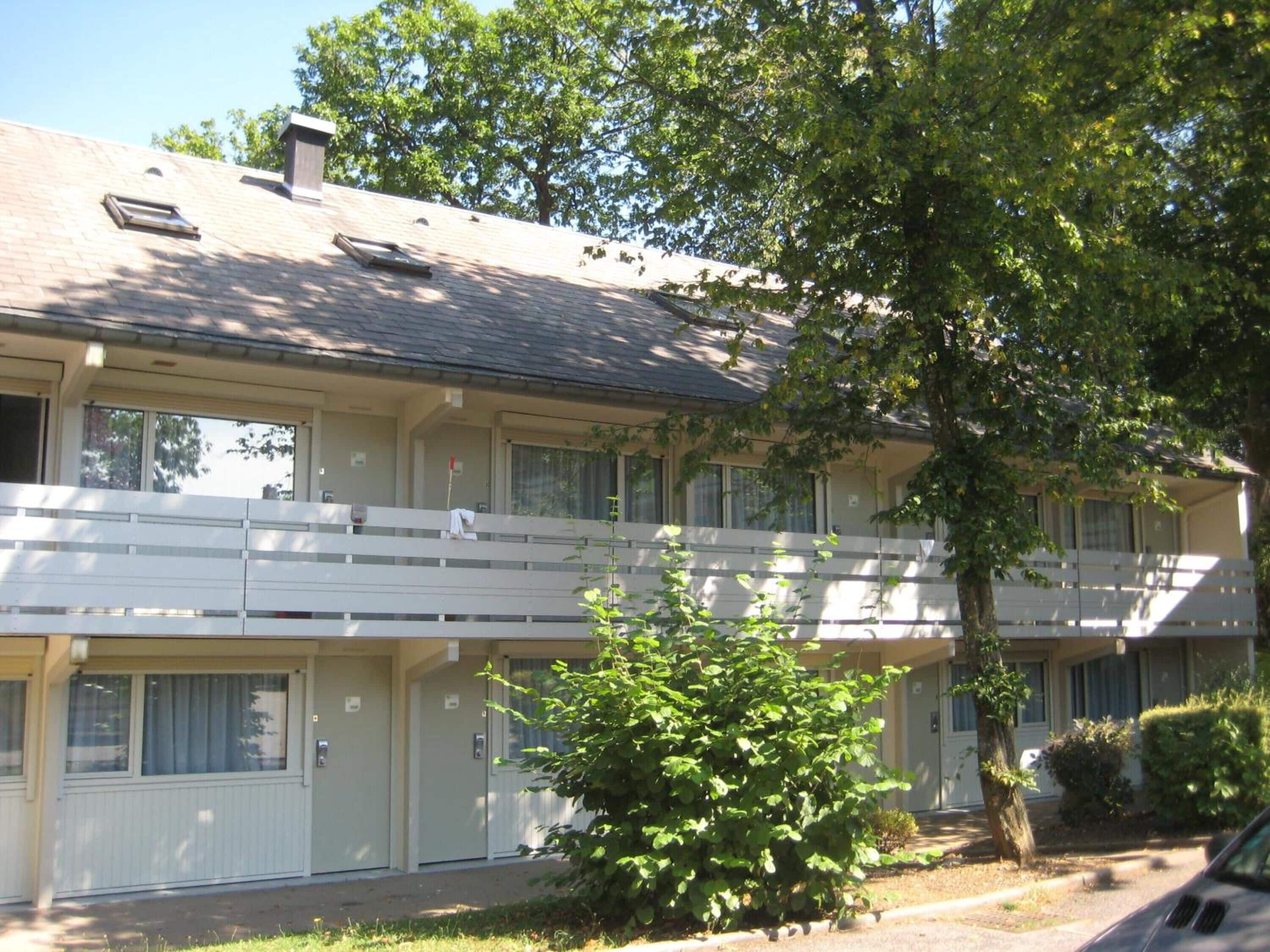 A two-story motel with a flat roof, multiple windows, and a covered outdoor area.