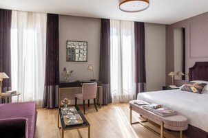 Una camera d'albergo con un letto, una scrivania, una sedia e un tavolino con vassoio.