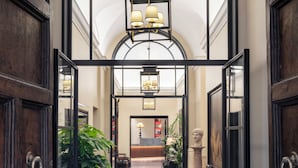 A hotel lobby with a checkered floor, a large arched window, and a chandelier. - Hotel Adriano Rooftop (Rome)