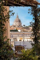 Un balcón con vistas a un edificio histórico con cúpula, rodeado de vegetación.
