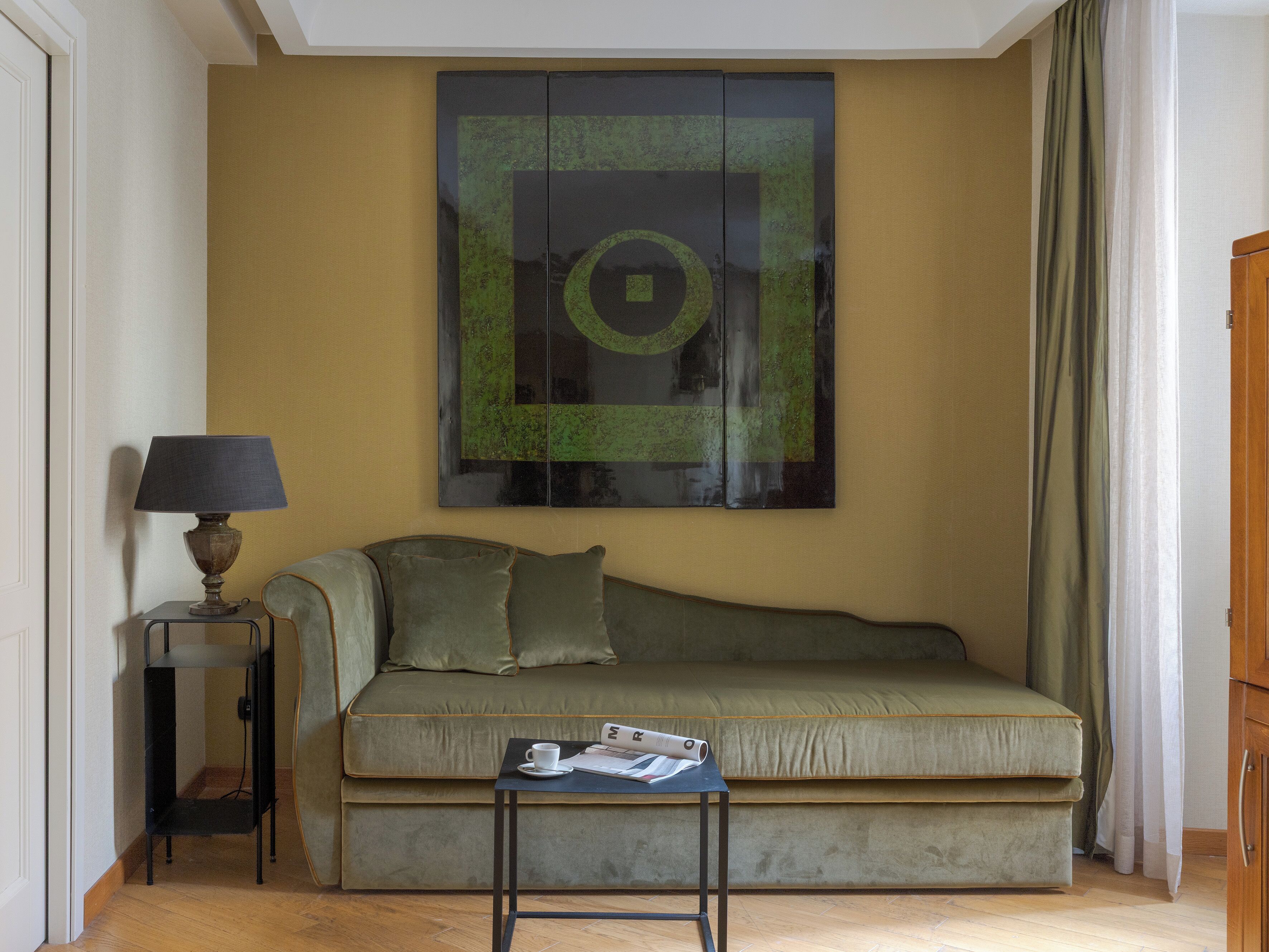 Una habitación con un sofá, una mesita con lámpara y una obra de arte en la pared.