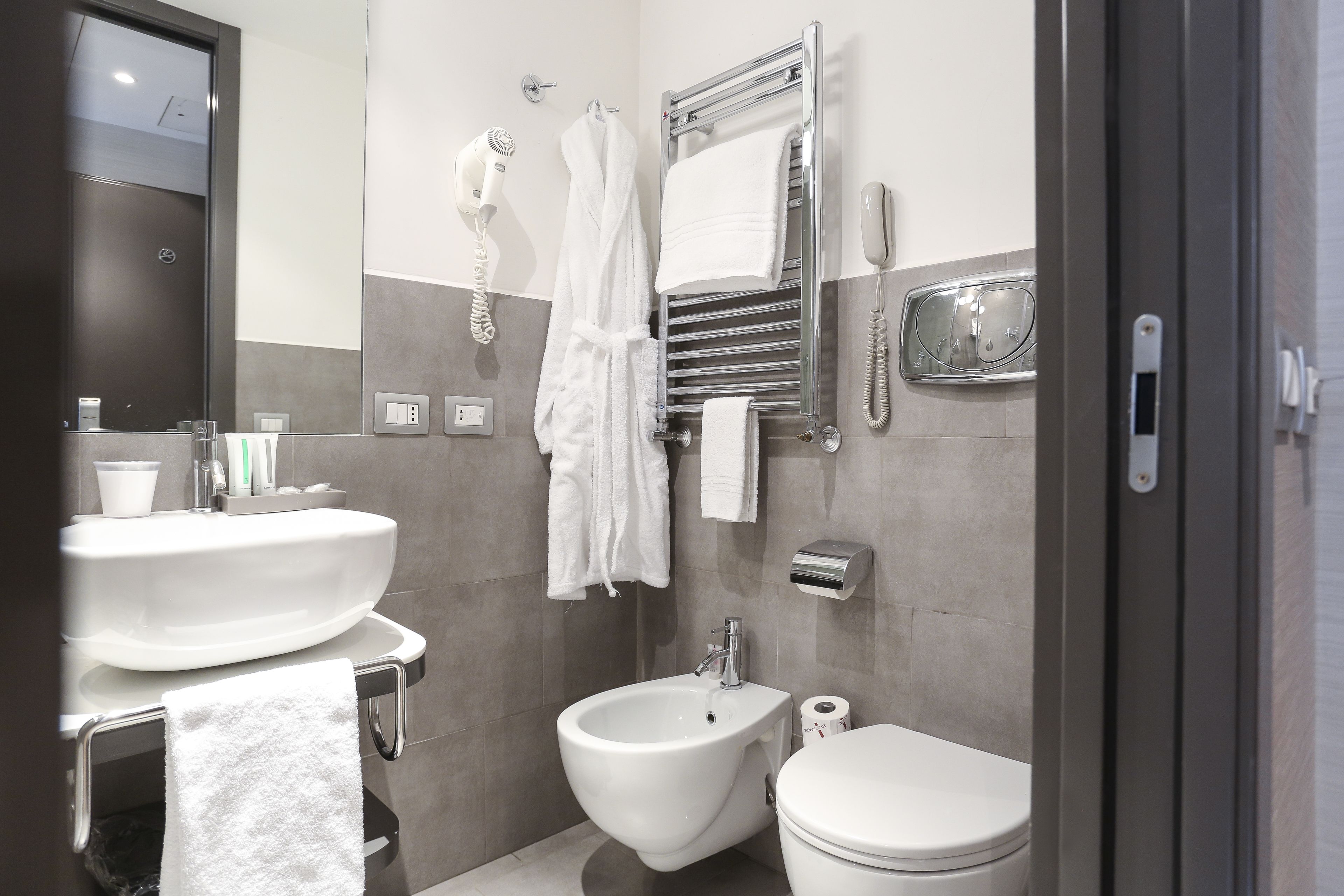 A modern bathroom with a bidet, toilet, sink, and towel rack.