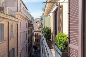 Un carrer estret amb edificis a ambdós costats, balcons amb baranes i un cel serè.