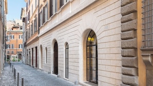 A cobblestone street lined with historic buildings featuring arched windows and stone facades. - Hotel Adriano Rooftop (Rome)