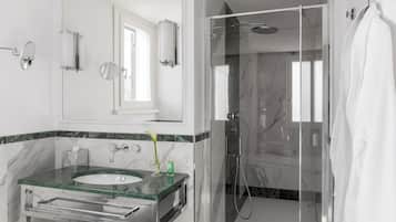 Un baño moderno con ducha de vidrio, lavamanos con azulejos de mármol y un espejo grande.