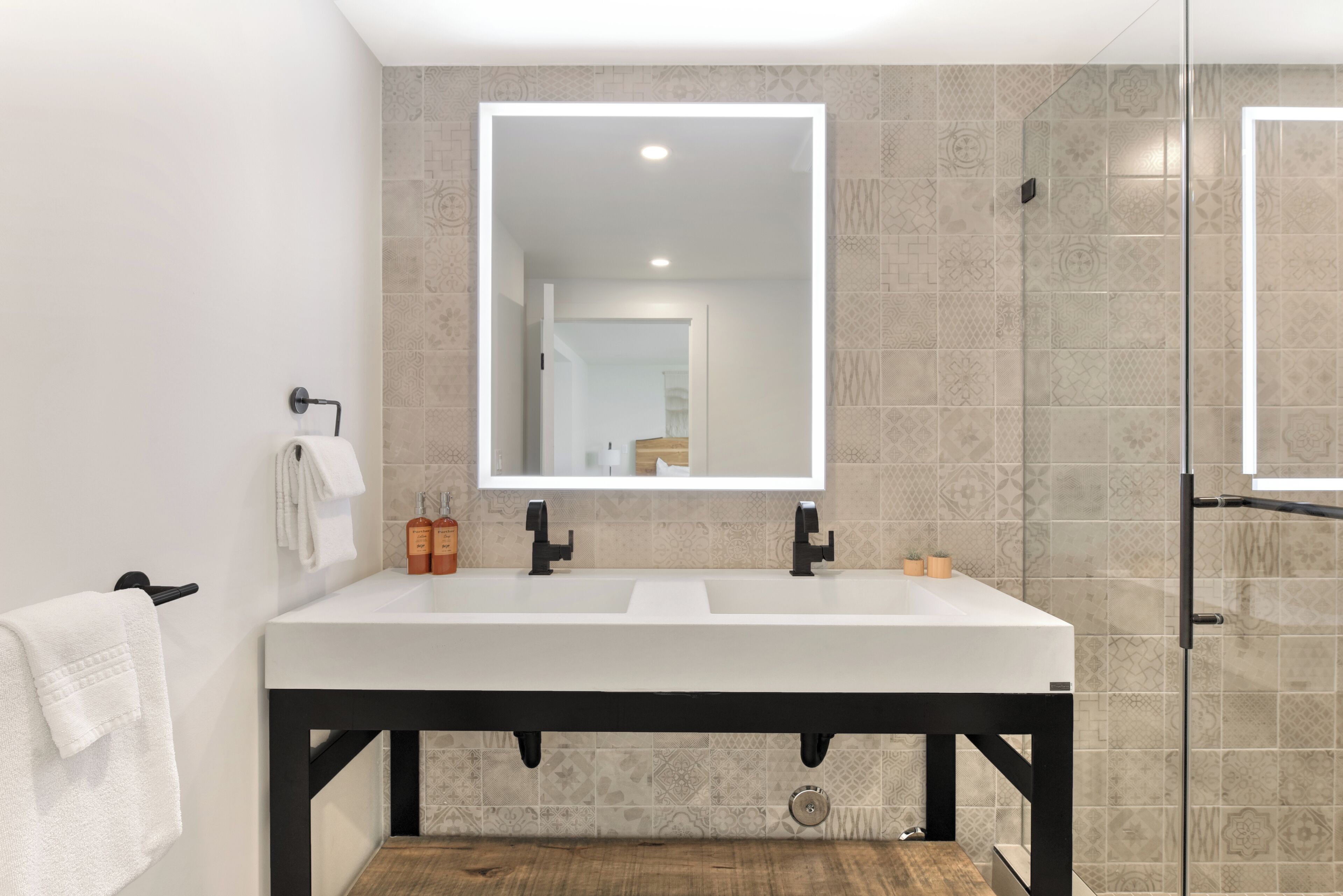 A modern bathroom with a white sink, black faucet, and a large mirror.