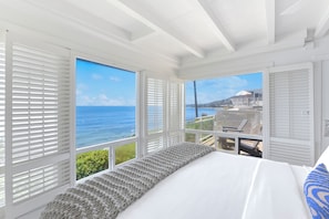A bedroom with a large window overlooking the sea, a bed with a grey knitted throw, and white shutters. - Laguna Surf Lodge by SCP Hotels (Laguna Beach)