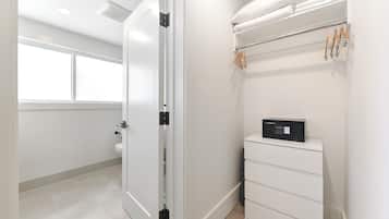 Un baño limpio y moderno con inodoro, un armario blanco y un perchero con toallas.