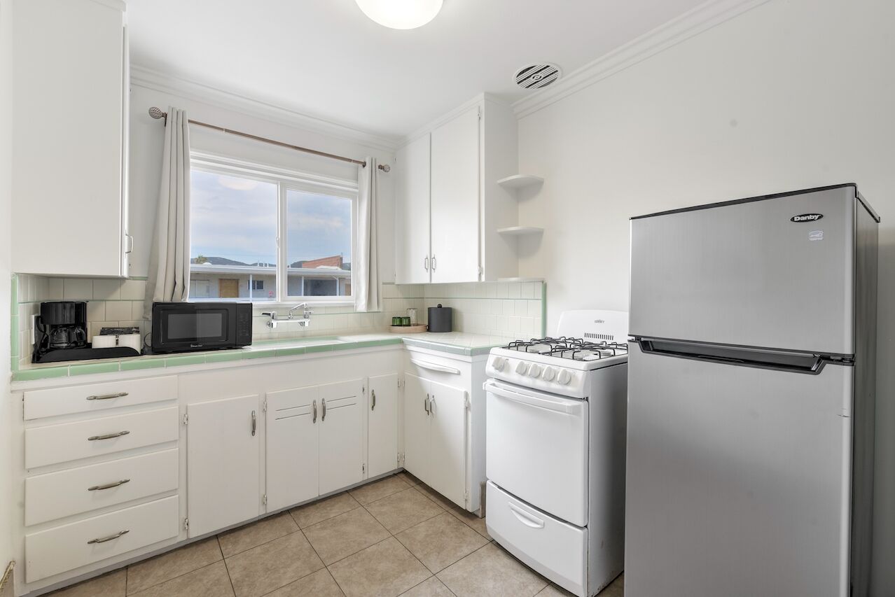 A kitchen with white cabinets, a gas stove, a microwave, and a refrigerator.