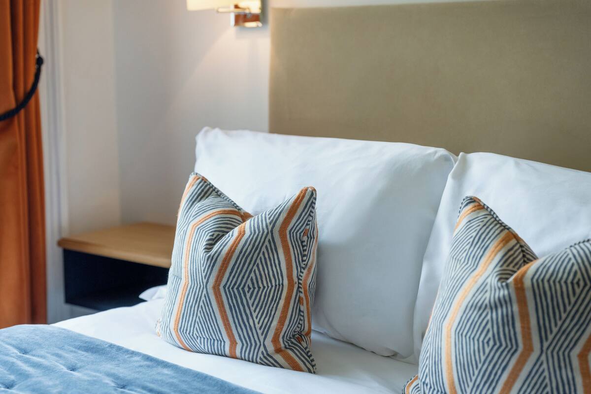 A bed with striped pillows, a headboard, and a bedside table.