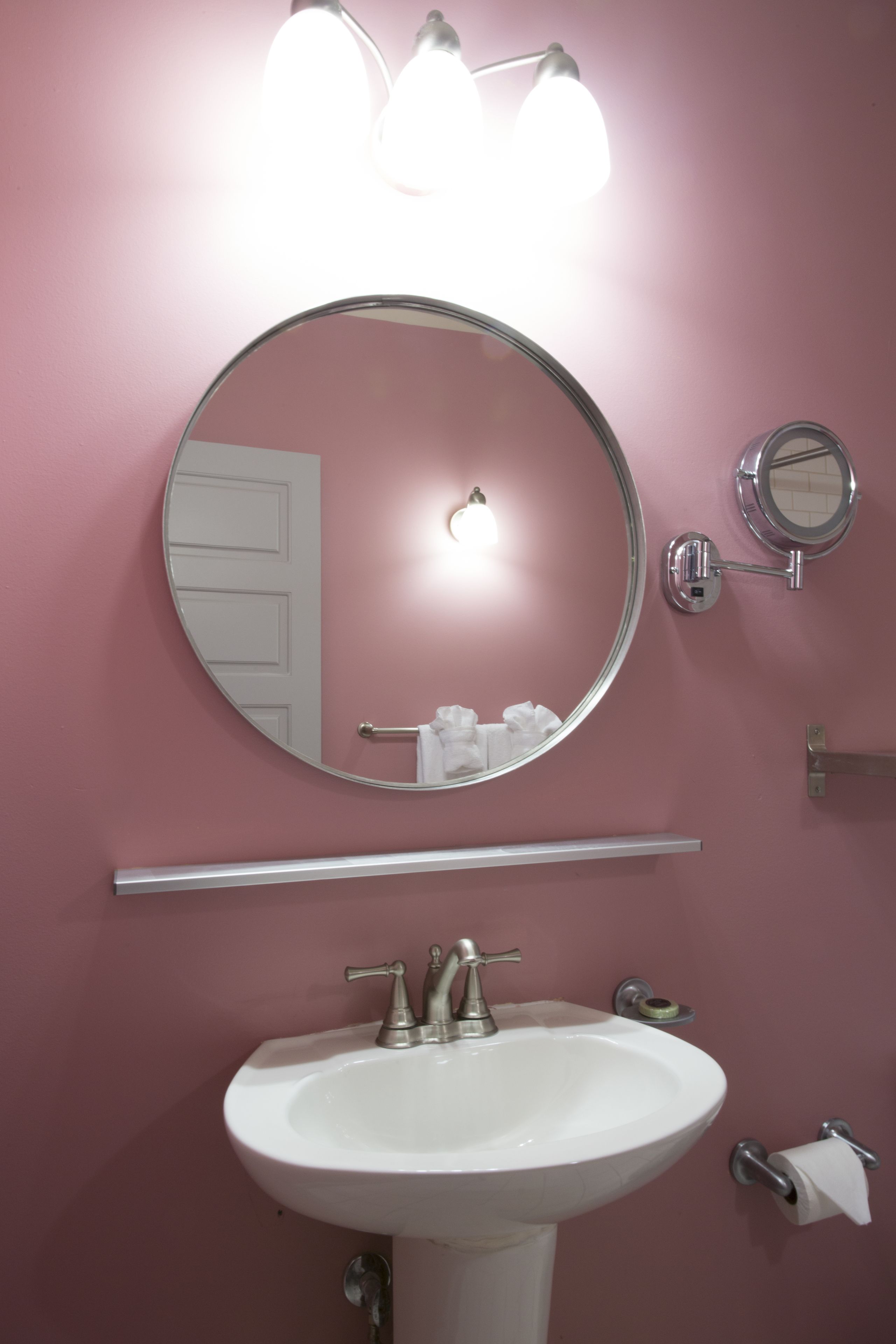 A bathroom with a white sink, a round mirror, and two wall-mounted light fixtures.