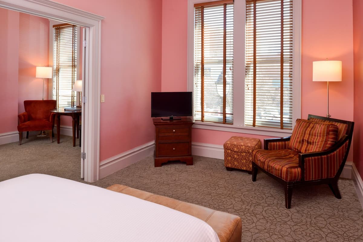 A hotel room with a bed, a TV, a chair, and a desk.