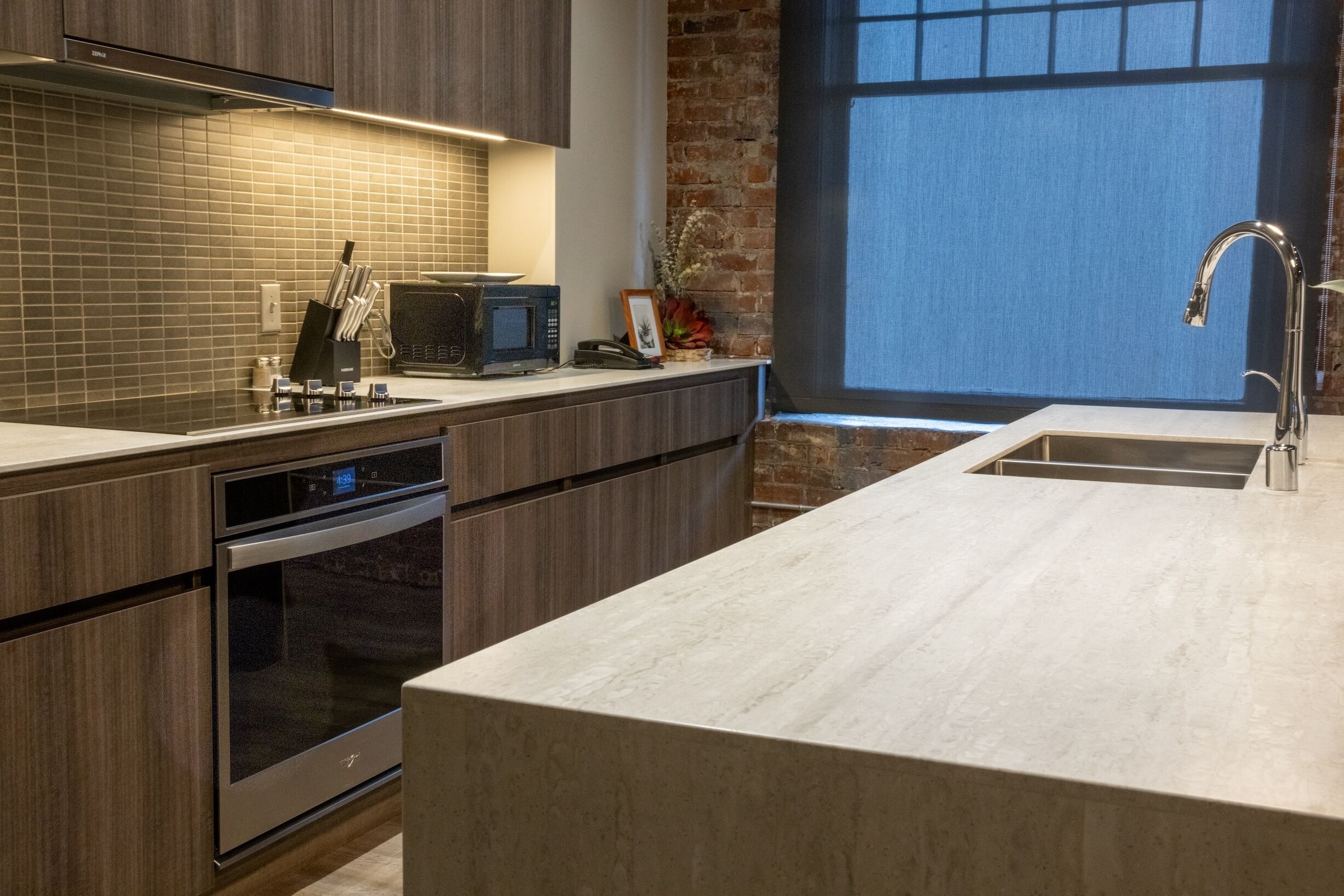 Una cucina moderna con forno a incasso, microonde e lavello in acciaio inossidabile.