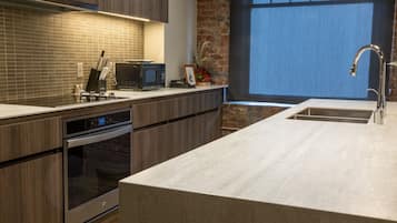 Una cocina moderna con horno empotrado, microondas y pileta de acero inoxidable.