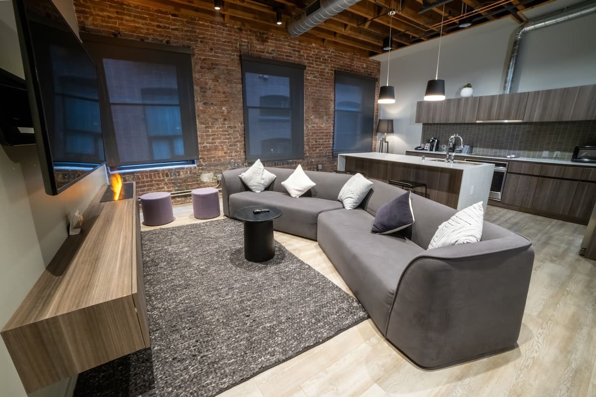 A modern living room with a grey sofa, a coffee table, and a TV mounted on the wall.